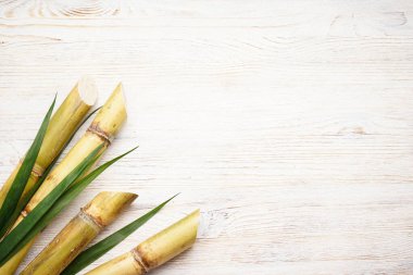 Beyaz masadaki şeker kamışı ve yeşil yaprak, yazı için yer. Üst görünüm.