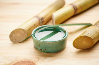 Yakın plan şeker kamışı ve tahta arka planda taze baston suyu..