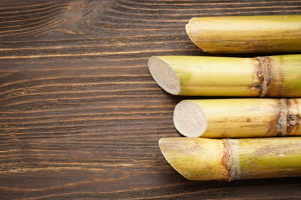 Ahşap arka planda şeker kamışına yakın plan, metin için yer var. Düz yatıyordu.