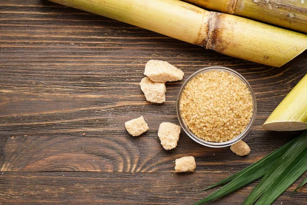 Tahta zemin üzerinde şeker kamışı ve esmer şeker ve metin için yer var. Üst görünüm.