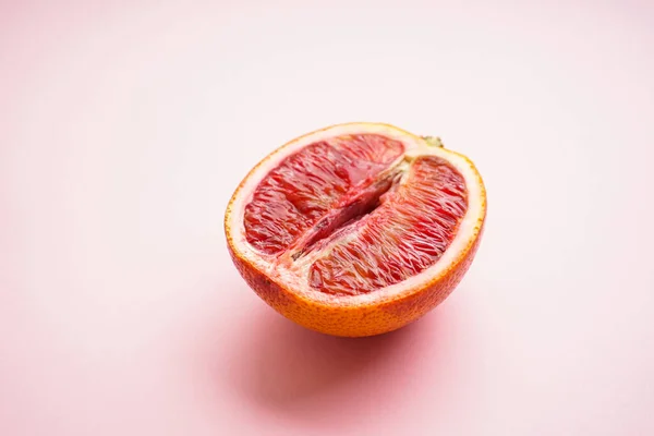 Pembe arka planda yarım kan portakalı. Seks konsepti 18+
