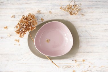 Ortanca, kurumuş çiçekler ve tahta arka planda tabaklar, üst manzara. Klasik stil.