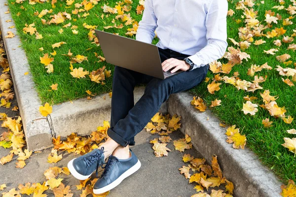 Young man using laptop in the park, autumn park and people.