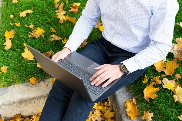 Young man using laptop in the park, autumn park and people.
