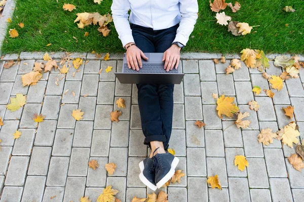 Young man using laptop in the park, top view.