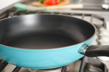 New frying pan on the stove, close-up. Fresh vegetables lie near the frying pan on the countertop.