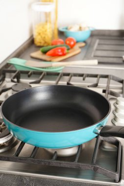 New frying pan on the stove, fresh vegetables lie on the countertop. Vertically.