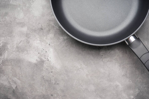 Новая сковородка и кухонный инструмент на заднем плане, пространство для текста. Вид сверху, плоский.