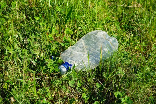 Plastic bottle on green grass, close-up.