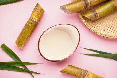 Fresh sugar cane juice and sugar cane on a pink background, top view.