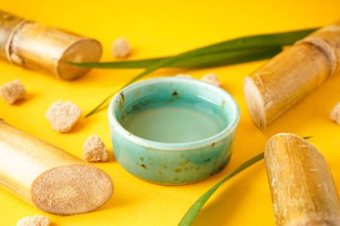 Fresh sugar cane juice and cane on a yellow background. Closeup.