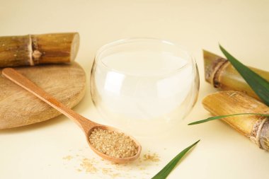 Fresh cane juice and brown sugar on a yellow background, close-up.