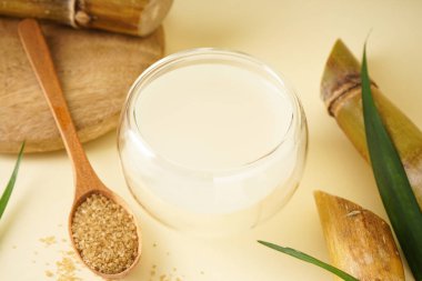 Fresh cane juice and brown sugar on a yellow background. Close-up.