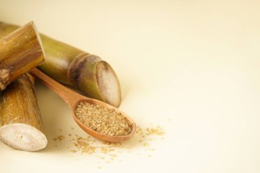 Granulated brown sugar, sugarcane on a yellow background, closeup. Space for text.