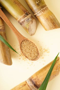Granulated brown sugar, sugarcane on a yellow background, close-up, top view. Vertically.
