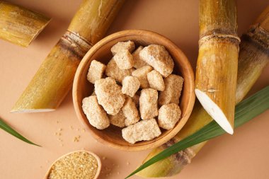 Granulated brown sugar, sugarcane on a brown background. Top view.