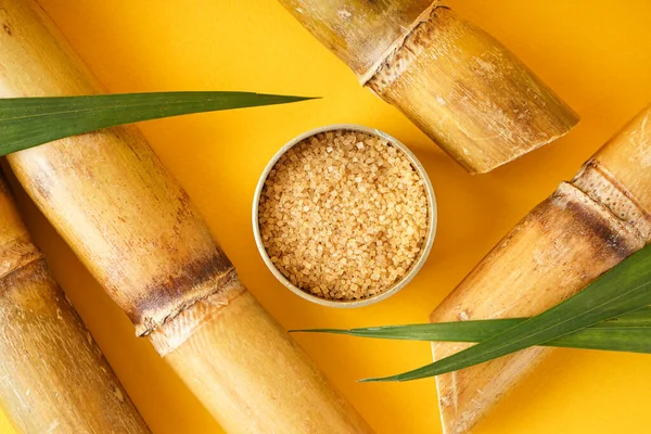 Brown sugar and sugar cane on a yellow background, close-up. Top view.