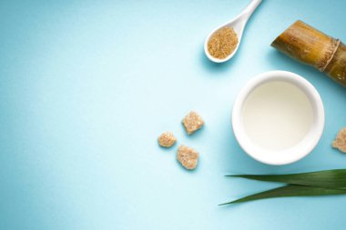Sugar cane juice and brown sugar on blue background with space for text.