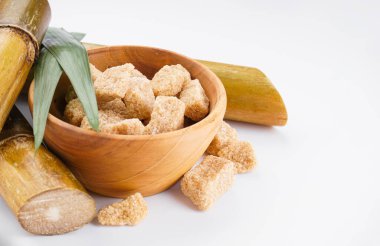Brown sugar and sugar cane on a white background with space for text, closeup.