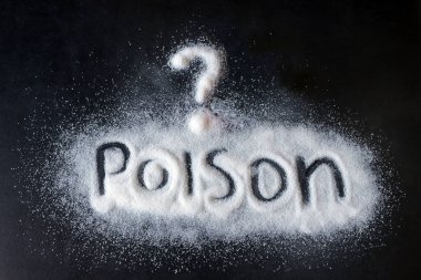 Beyaz toz siyah bir yüzeye dağılmış. Yazılı kelime: Zehir. Kavram zehirlenmesi, aşırı tuz, şeker ve gıda katkı maddeleri tüketimi..