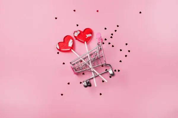 Zwei Rote Lutscherförmige Herzen Mini Einkaufswagen Auf Rosa Hintergrund Konfetti Stockbild