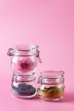 Japon kibrit çayından farklıdır. Pembe arka plandaki cam kavanozlarda yeşil ve mavi. Acai böğürtlen tozu yeşil çay yaprağı tozu.