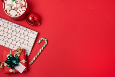 Klavye ve Noel hediyeli çalışma alanı ve kırmızı zemin üzerinde şeker kamışı düz bir görünüm, kopyalanmış uzay, kopyalanmış noel tatili konsepti online alışveriş