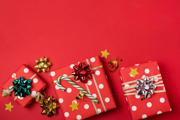 リボンと赤い背景に弓で包まれた3つのギフトボックスクリスマスフェスティバルの休日の背景コピースペース — ストック写真
