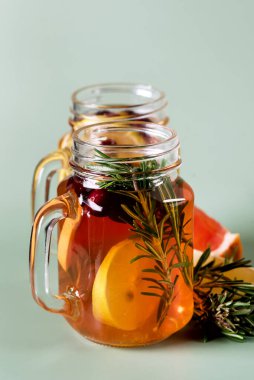 Limonlu buzlu çay ve cam kavanozlarda taze biberiye, yeşil arka plan sağlık yaz içeceği, dikey.