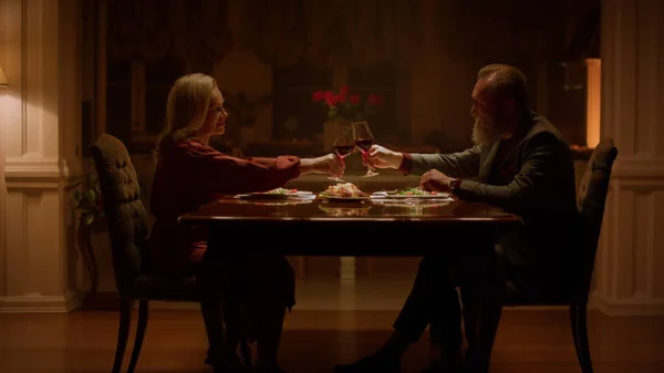 Dragoste cuplu în vârstă clinking ochelari la cină romantică în casa de seară fotografii de stoc fără drepturi de autor