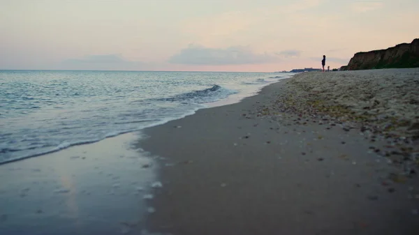 Watergolven spetteren op het strand. Vrouw silhouet wandelen zandstrand kust — Stockfoto