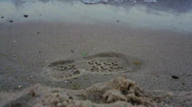 Yakından mavi deniz dalgaları kumsalda ayak izlerini temizliyor. Doğa arkaplanı