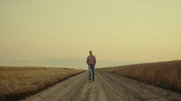 Малый бизнес агроном пересекает закат сельской местности с золотым полем в одиночку.