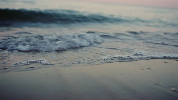 Las olas del mar salpicando playa de arena en la costa en la mañana fría. Superficie del agua — Foto de Stock
