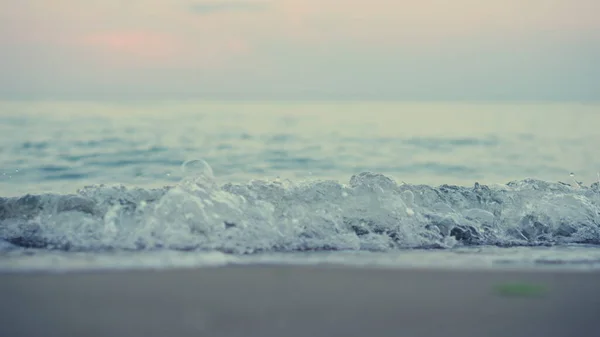 Primer plano olas azules del mar salpicando playa de arena de la costa en cámara lenta en el cielo rosa — Foto de Stock