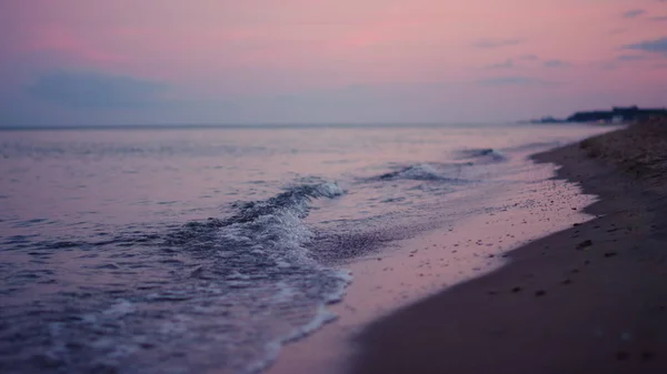 Cielo porpora che riflette alla superficie dell'acqua di mare al tramonto freddo di sera. Onde calme — Foto Stock