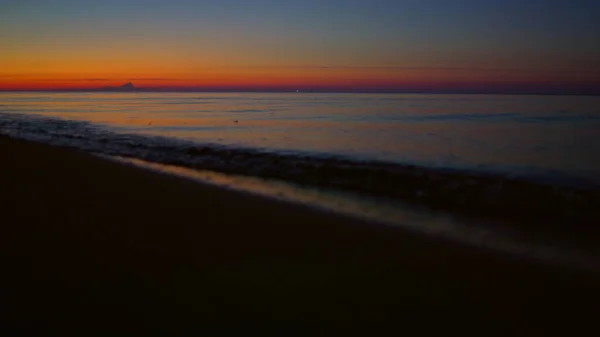 Goldener Sonnenaufgang, der sich am Morgen in der Oberfläche des Meerwassers spiegelt. Wasserwellen plätschern — Stockfoto