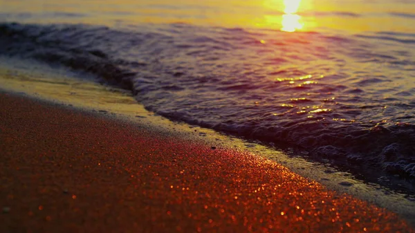 Nahaufnahme Ozeanwellen brechen Sandstrand in Zeitlupe bei orangefarbenem Sonnenuntergang — Stockfoto