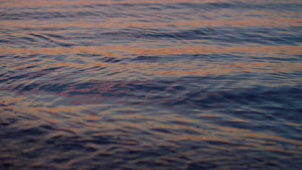 Primo piano superficie dell'acqua di mare che riflette il cielo viola all'alba tramonto della sera. — Foto Stock