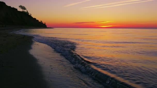 Gyönyörű kilátás sziklás tengerparton ellen fényes narancssárga naplemente este. — Stock videók