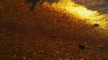 Sakin okyanus dalgaları altın kumsala vuruyor. Turuncu gün doğumu deniz suyunu yansıtır