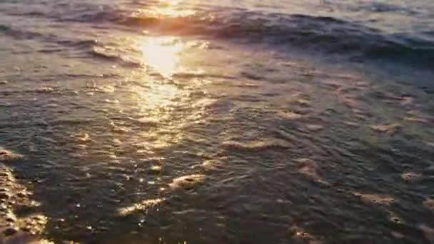 Spokojne fale morskie pluskające piaskiem plażowym w słoneczny poranek. Złoty wschód słońca odzwierciedlający — Wideo stockowe
