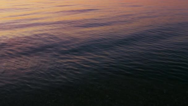 Fechar a superfície calma da água do oceano refletindo o céu rosa brilhante do nascer do sol na manhã — Vídeo de Stock