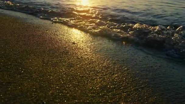 Отражение солнечного света в морских волнах, плескающихся пляжным песком на золотом восходе солнца — стоковое видео