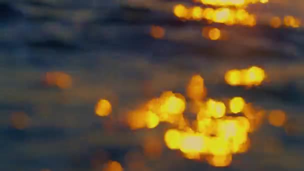 Rozproszone fale oceaniczne plamiące złotą plażę. Odbicie pomarańczowego słońca — Wideo stockowe