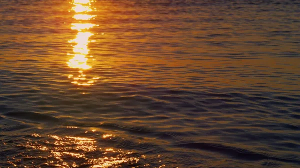 Blick auf das Meerwasser, das Sonnenstrahlen an der Küste reflektiert. Ruhiger Sonnenaufgang am Strand. — Stockfoto