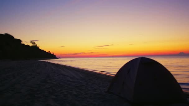 Tenda de acampamento na praia de areia escura ao amanhecer dourado. Parque de campismo ocean seashore — Vídeo de Stock