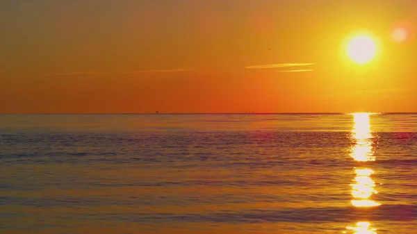 Tranquil view of orange sun reflecting in clear blue ocean water in on sunset. — Stock Photo, Image
