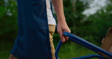 Tarımsal ekipman kullanan bir çiftçi. Agronomistlerin elleri meyve bahçesinde araba kutusu taşır..