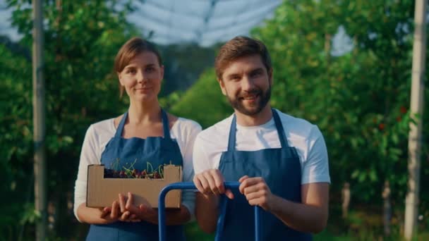 Jordbrukare laget ser kamera som håller körsbär gröda i solig trädgård plantage — Stockvideo